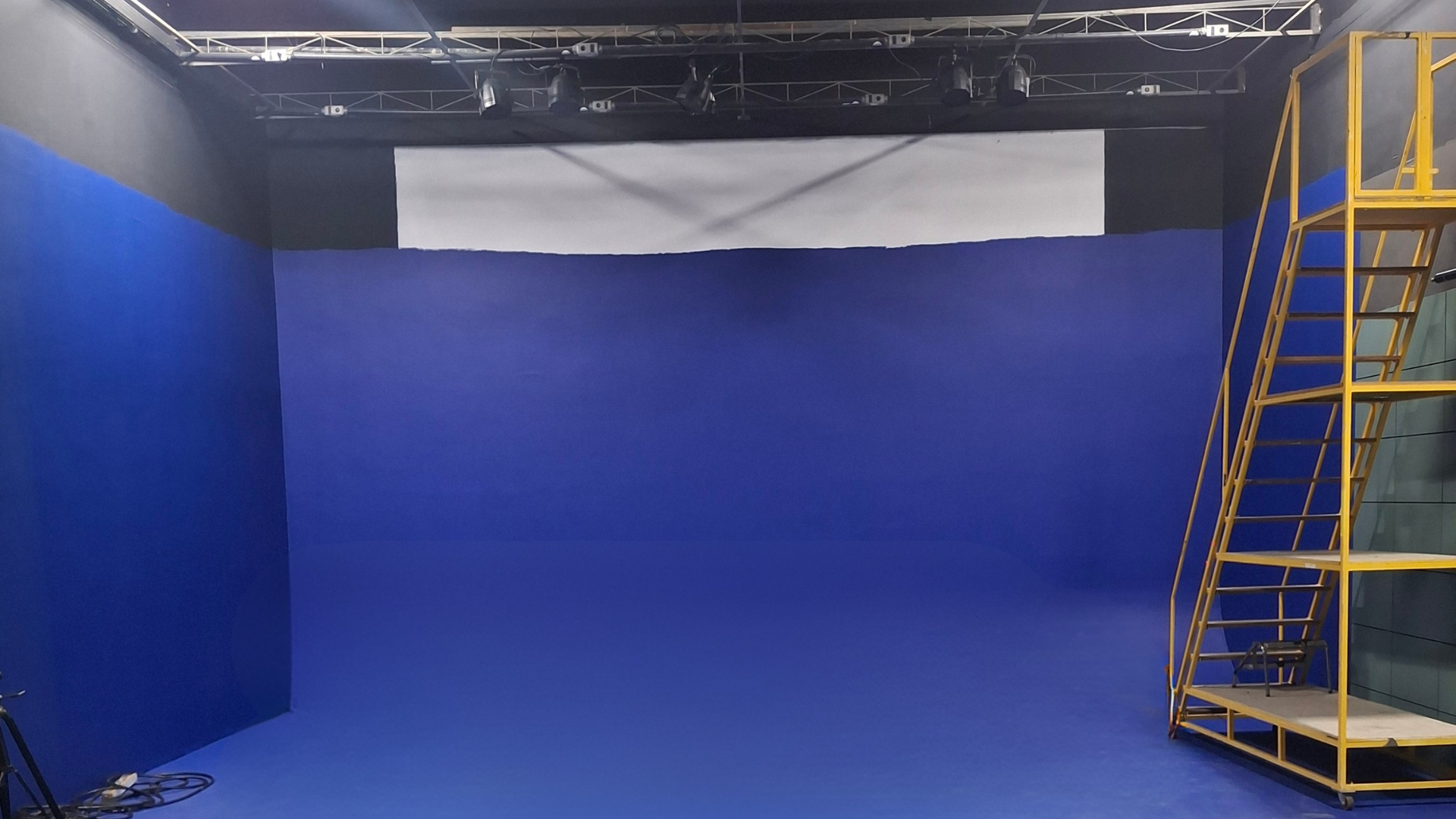 Estúdio 1 — ciclorama azul com grid de iluminação e estrutura de apoio